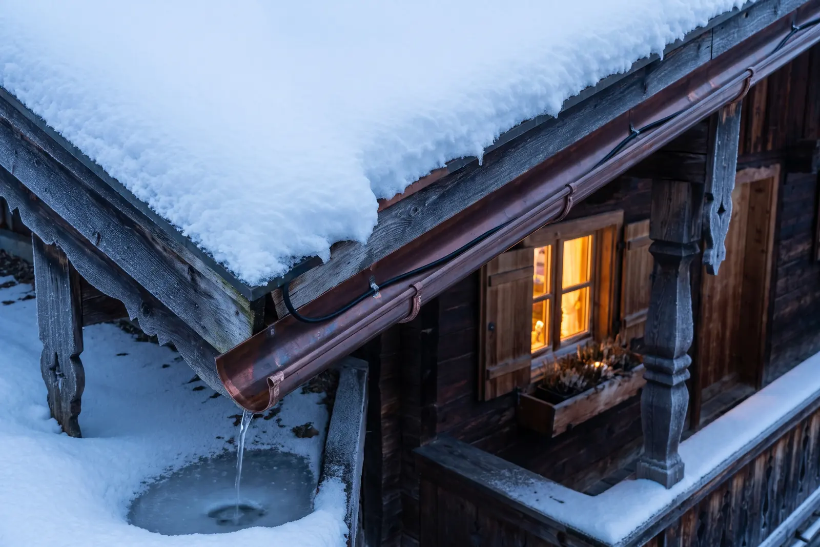 Dachrinne mit Heizleitung, frei von Eis, unter einem verschneiten Dach
